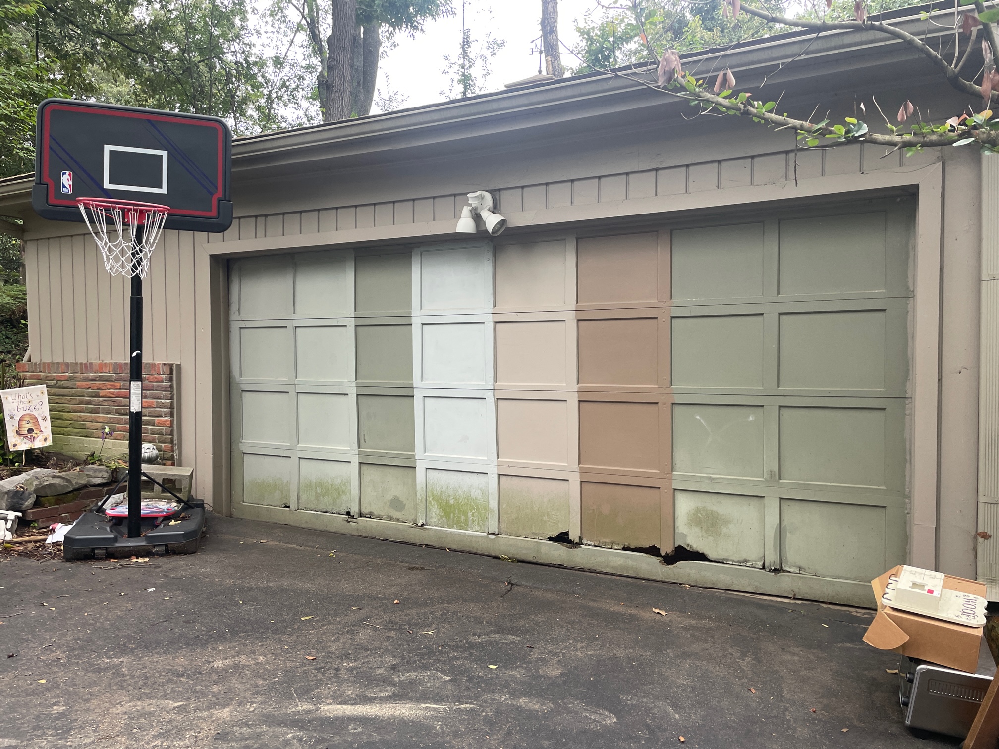 Before view of an aging multicolor garage door with damaged lower panels