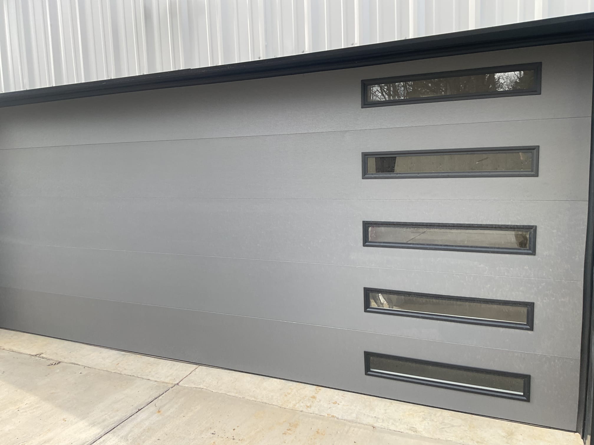 Modern gray garage door with a vertical row of horizontal windows