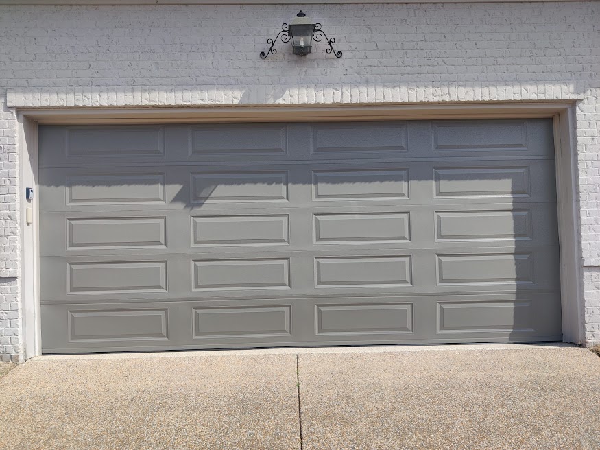 Finished modern gray recessed-panel garage door on a white brick home in Greater Memphis