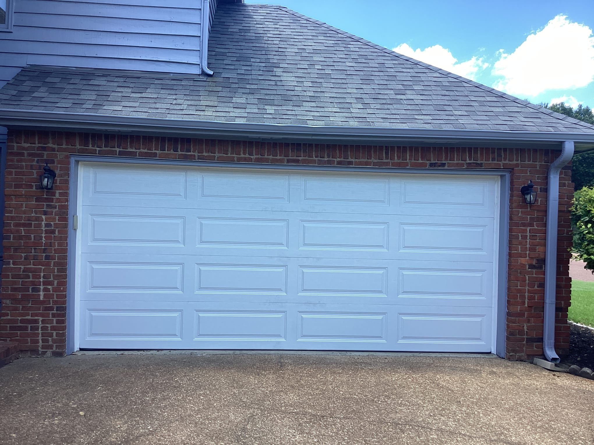 Finished classic white garage door with rectangular raised panels on a brick home