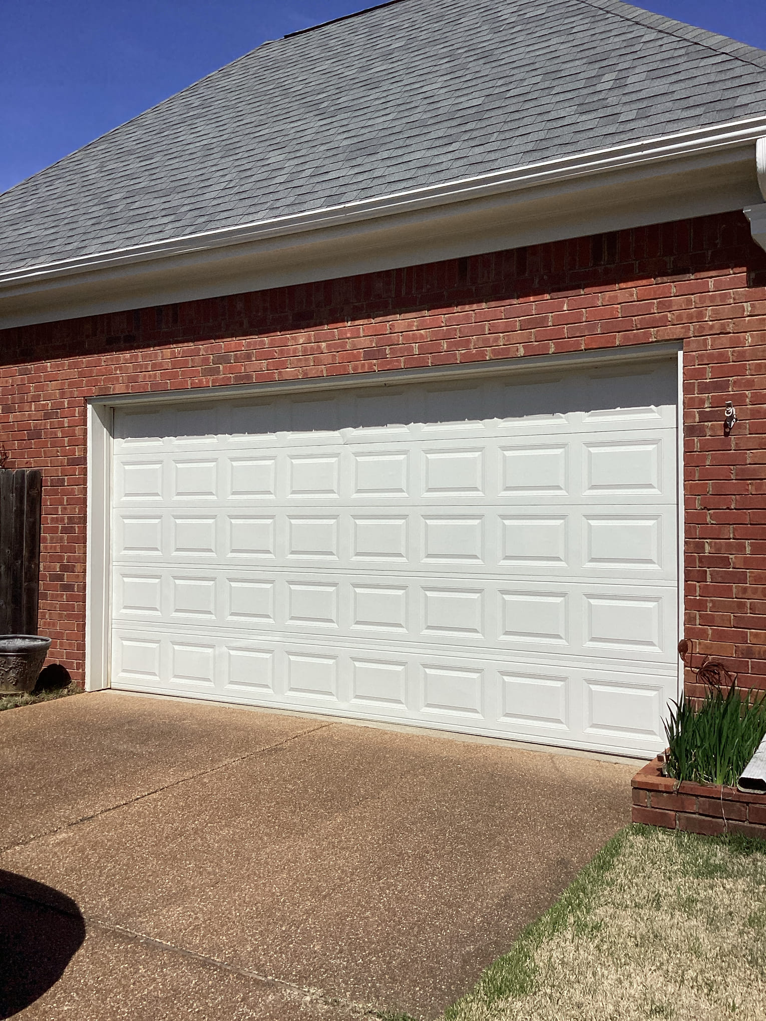 Finished white raised-panel garage door installed on a brick home in Greater Memphis