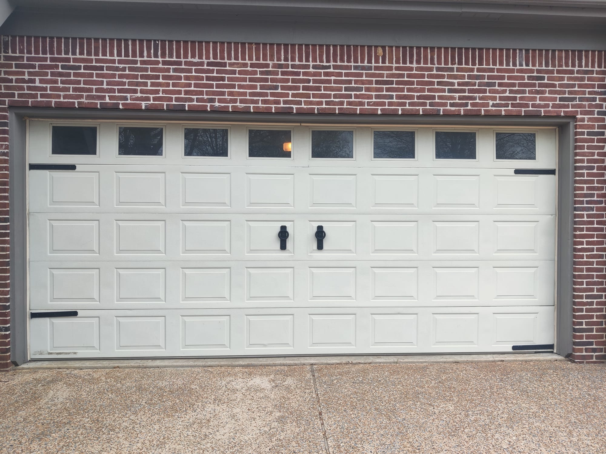 White carriage-style garage door with square windows and decorative hardware